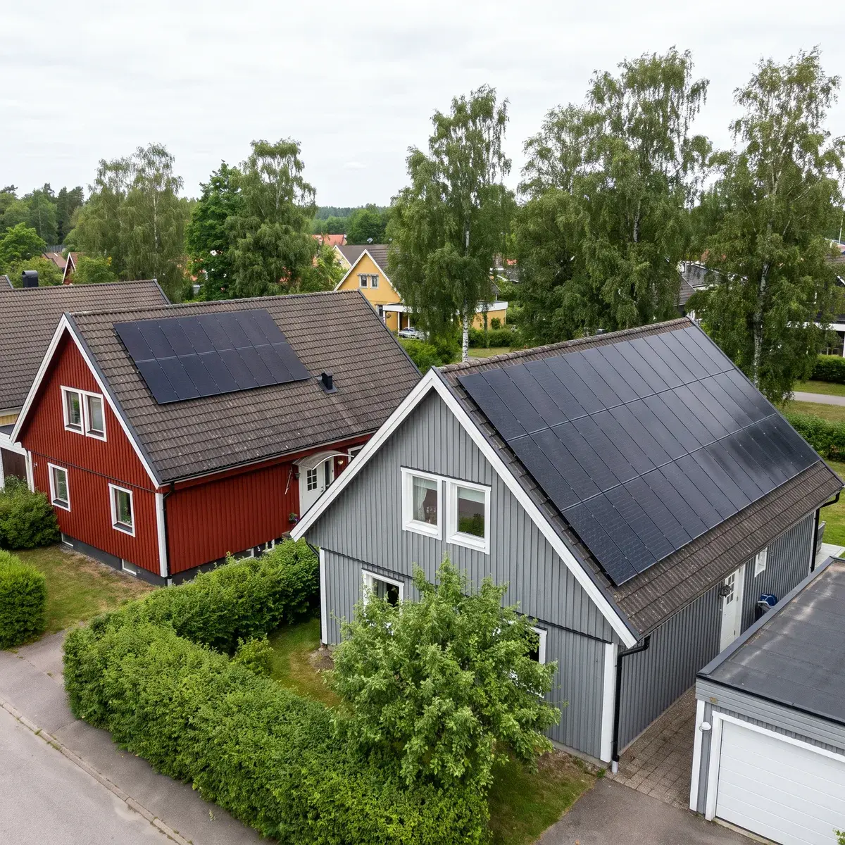 Två grannvillor sedda ovanifrån: den röda har en liten anläggning med DualSun FLASH-paneler, den grå har hela takfallet täckt.