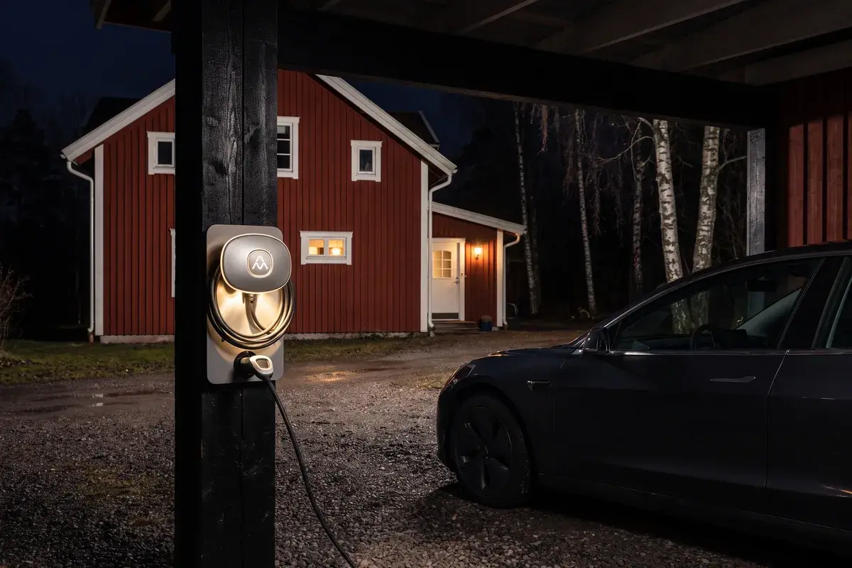 Charge Amps Halo laddar en elbil i en carport vid ett falurött trähus mitt i natten.